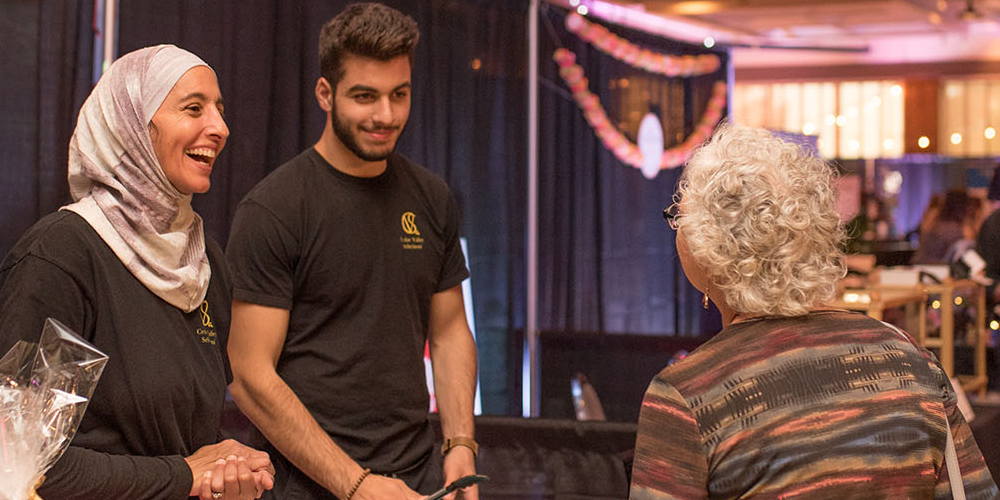 Ameen & Surria Fadel, founders of Cedar Valley, speaking with a trade show attendee